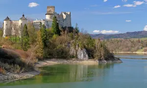 Zamek na skale nad jeziorem, jeden z najpiękniejszych zamków w Małopolsce, otoczony zielenią i górami.
