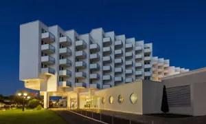 Nowoczesny hotel Amber Baltic w Międzyzdrojach o architekturze z balkonami w kształcie schodków, oświetlony wieczorem.