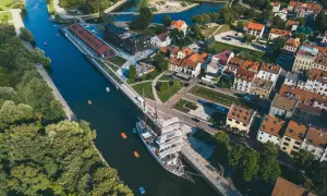 Widok z lotu ptaka na miasto na Litwie z kanałem, żaglowcem i kolorowymi łódkami.