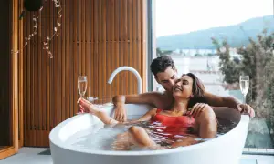 Para relaksu we dwoje w hotelu bez dzieci. Para w wannie z szampanem, z widokiem na góry.