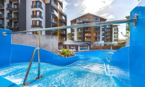 Basen z falą i zjeżdżalnią w hotelu Blue Mountain w Szklarskiej Porębie. Nowoczesne budynki hotelowe w tle.