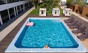 Relaks w basenie w hotelu w Karpaczu. Różowy flaming unosi się na wodzie, a obok leżaki i zaciszne altanki. Idealne miejsce na wakacje.