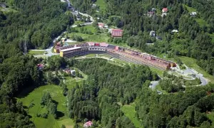 Widok z lotu ptaka na Orle Gniazdo w Szczyrku, rozległy budynek hotelowy otoczony zielonymi lasami i polanami.