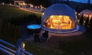 Nocny widok na hotel na szczycie góry. Dwie kopuły, jedna z wanną i łóżkiem, druga z jacuzzi na zewnątrz.