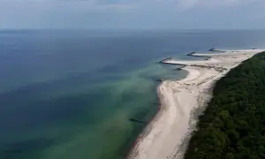 Widok z lotu ptaka na plażę w Jarosławcu z kamiennymi falochronami tworzącymi kształt przypominający molo.