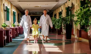 Rodzina w szlafrokach idzie korytarzem hotelowym. To idealne miejsce, by poczuć, co to jest spa i odpocząć.