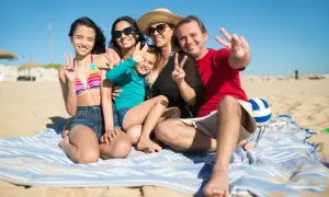 Rodzina cieszy się wakacjami z dziećmi w Polsce na plaży. Wszyscy pozdrawiają, pokazując znak pokoju.