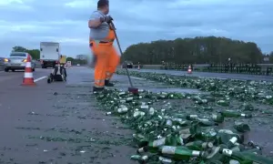Drogi z butelkami piwa, z czym kojarzą się Niemcy. Pracownik w pomarańczowym kombinezonie sprząta autostradę.
