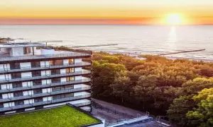 Idealny urlop nad morzem z wyżywieniem: nowoczesny hotel z widokiem na zachód słońca nad Bałtykiem, otoczony zielenią.