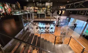 Wnętrze muzeum sportu w Warszawie. W gablotach pamiątki, puchary i zdjęcia. Schody prowadzą do kolejnych ekspozycji.