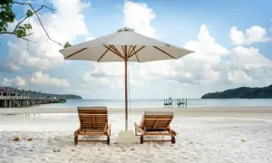 Dwie leżaki pod parasolem na piaszczystej plaży. Idealne miejsce, by zapytać, gdzie na wakacje w czerwcu.