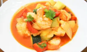 Pyszna cataplana z krewetkami, papryką i cukinią w aromatycznym sosie pomidorowym, udekorowana świeżą kolendrą.