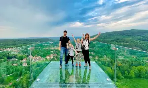 Rodzina na szklanym tarasie najwyższej wieży widokowej w Polsce. Zachwycający widok na zielone wzgórza i miasteczko.