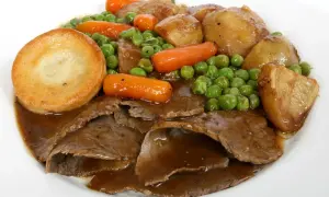 Tradycyjne jedzenie w Wielkiej Brytanii: pieczona wołowina, ziemniaki Yorkshire, marchewka i groszek w sosie.