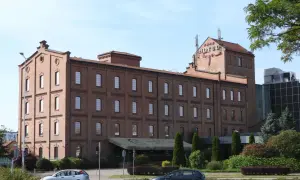 Hotel Młyn we Włocławku, ceglany budynek z czerwonym napisem HOTEL na dachu, otoczony zielenią.