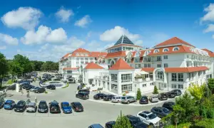 Elegancki hotel 5 gwiazdkowy nad morzem z przestronnym parkingiem pełnym samochodów.