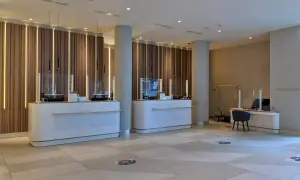 Eleganckie recepcje w Radisson Collection Hotel Warsaw, z nowoczesnym oświetleniem i marmurowymi blatami, zapraszają do komfortowego zameldowania.