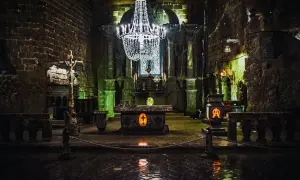 Wnętrze kaplicy w kopalniach soli w Wieliczce i Bochni. Kryształowy żyrandol oświetla ołtarz i kamienne rzeźby.