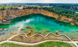 Turkusowe, magiczne jeziora w Polsce, dawny kamieniołom z drewnianą kładką i altanką, otoczony lasem i skalnymi zboczami.