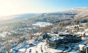 Zimowy krajobraz z hotelem Elements, który oferuje idealny hotel ze stokiem. Wokół ośnieżone drzewa i góry.