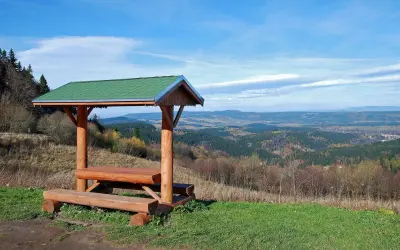 Drewniana wiata z ławami i stołem na tle malowniczego krajobrazu zieleniec góry.