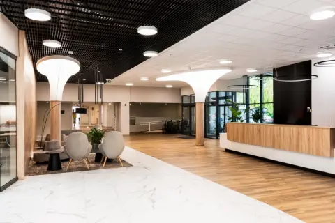 Nowoczesne wnętrze recepcji sanatorium Argentyt Dąbki z wygodnymi fotelami i drewnianą ladą.