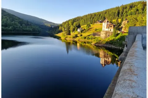 Spokojna tafla jeziora odbija zamek i zielone wzgórza. Szpindlerowy Młyn atrakcje latem to idealne miejsce na relaks.