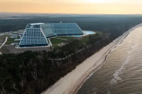 Nowo otwarty hotel nad morzem, z basenem i widokiem na plażę i las. Architektura przypomina schody.
