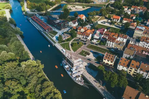 Widok z lotu ptaka na miasto na Litwie z kanałem, żaglowcem i kolorowymi łódkami.