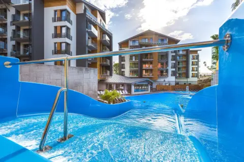 Basen z falą i zjeżdżalnią w hotelu Blue Mountain w Szklarskiej Porębie. Nowoczesne budynki hotelowe w tle.