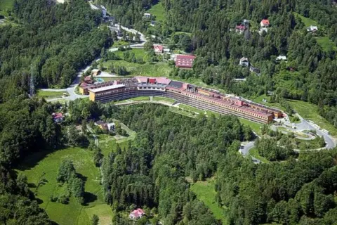 Widok z lotu ptaka na Orle Gniazdo w Szczyrku, rozległy budynek hotelowy otoczony zielonymi lasami i polanami.