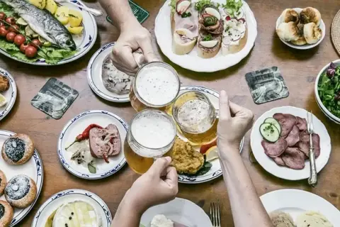 Uczta z daniami kuchni czeskiej: ryba, kiełbasa, pieczywo, piwo i słodkie wypieki.