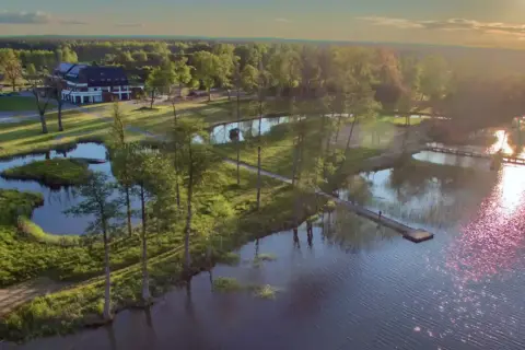 Malownicze mazury miejscowości nad jeziorem. Hotel z pomostami i zielenią, idealne miejsce na wypoczynek.