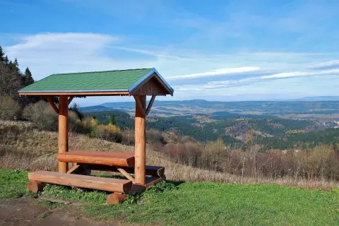 Drewniana wiata z ławami i stołem na tle malowniczego krajobrazu zieleniec góry.
