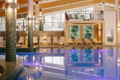 Basen w hotelu z leżakami i widokiem na góry.