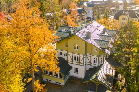 Jesienny hotel w Szklarskiej Porębie otoczony złotymi drzewami. Widok z góry na architekturę górską.