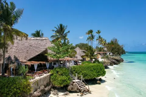 Rajski widok na Zanzibar, idealny czas na wakacje. Tropikalna plaża z palmami, kamiennymi schodkami i restauracją pod strzechą.