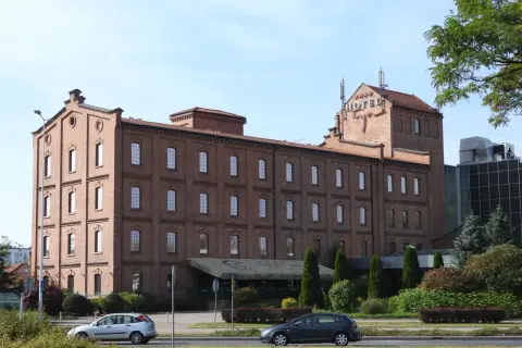 Hotel Młyn we Włocławku, ceglany budynek z czerwonym napisem HOTEL na dachu, otoczony zielenią.