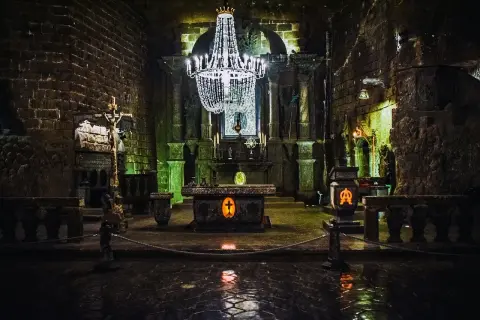 Wnętrze kaplicy w kopalniach soli w Wieliczce i Bochni. Kryształowy żyrandol oświetla ołtarz i kamienne rzeźby.