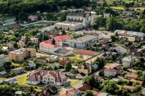 Widok z lotu ptaka na Janów Podlaski. Widać zabudowania, kościół i tereny zielone. Atrakcje tego miejsca zachęcają do odwiedzin.