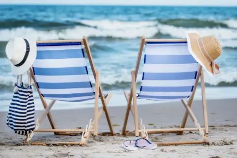 Dwa leżaki na plaży, gotowe na relaks. Idealne atrakcje nad morzem dla każdego, kto szuka słońca i fal.