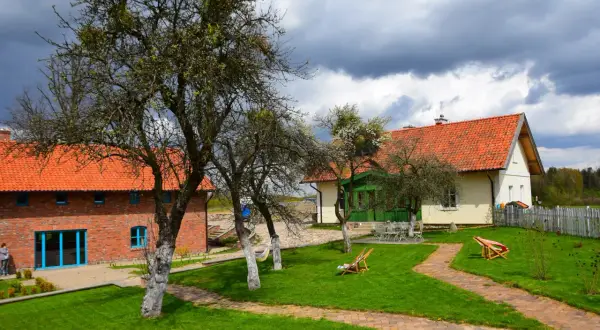 Malownicze zabudowania z cegły i tynku, z pomarańczowymi dachami, otoczone zielonym ogrodem. Idealne na weekend we dwoje w Polsce.