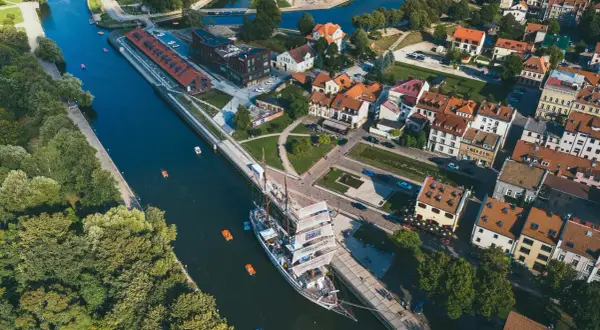 Widok z lotu ptaka na miasto na Litwie z kanałem, żaglowcem i kolorowymi łódkami.
