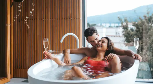 Para relaksu we dwoje w hotelu bez dzieci. Para w wannie z szampanem, z widokiem na góry.