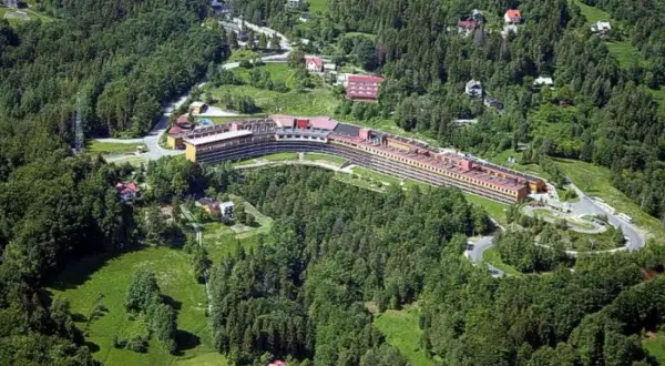 Widok z lotu ptaka na Orle Gniazdo w Szczyrku, rozległy budynek hotelowy otoczony zielonymi lasami i polanami.