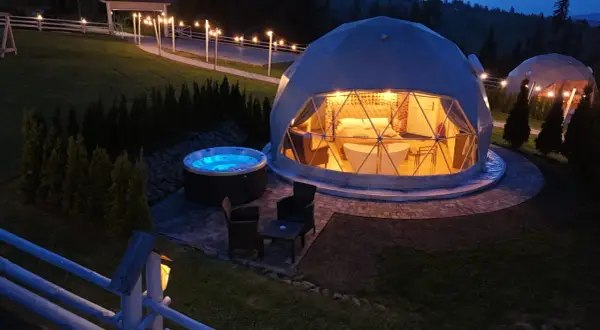 Nocny widok na hotel na szczycie góry. Dwie kopuły, jedna z wanną i łóżkiem, druga z jacuzzi na zewnątrz.