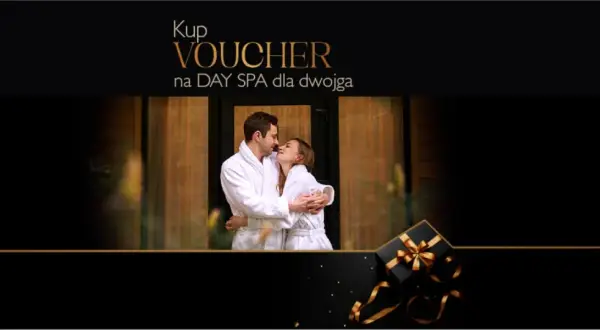 Para dwojga w szlafrokach przytulająca się na tle drewnianych drzwi. Obok czarny prezent ze złotą wstążką. Idealny voucher na weekend w spa dla dwojga.