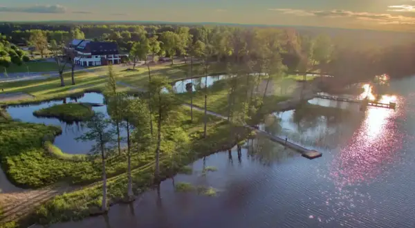 Malownicze mazury miejscowości nad jeziorem. Hotel z pomostami i zielenią, idealne miejsce na wypoczynek.