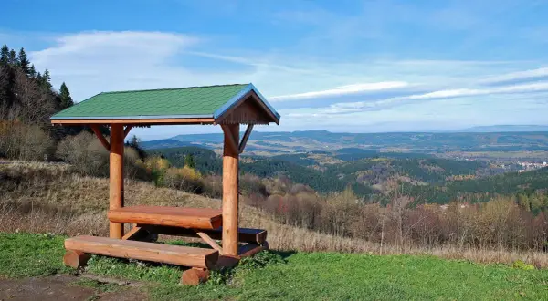 Drewniana wiata z ławami i stołem na tle malowniczego krajobrazu zieleniec góry.