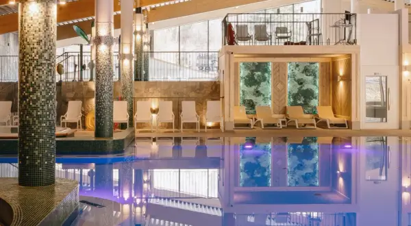 Basen w hotelu z leżakami i widokiem na góry.